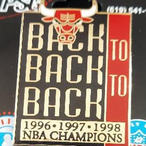 May include: A black and red enamel pin with a gold outline. The pin features a Chicago Bulls logo with the text "Back to Back to Back 1996-1997-1998 NBA Champions".
