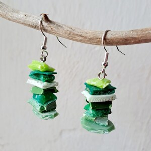 Può includere: Un paio di orecchini in vetro verde e bianco a strati con ganci d'argento. Gli orecchini sono impilati con diverse tonalità di vetro verde e bianco.