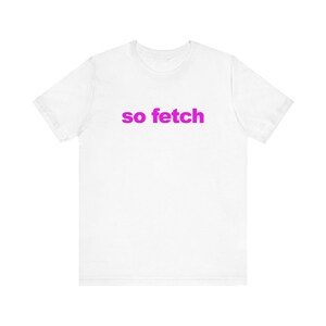 Może przedstawiać: Biała koszulka z nadrukiem "so fetch" w kolorze różowym.