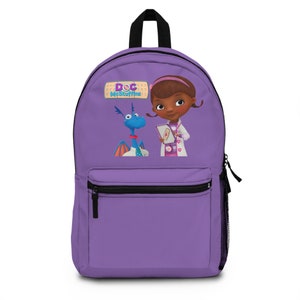 Puede incluir: Mochila morada con un diseño de Doc McStuffins que presenta a Doc McStuffins y a su amigo dragón, Stuffy. La mochila tiene una cremallera negra y un bolsillo negro en la parte delantera.