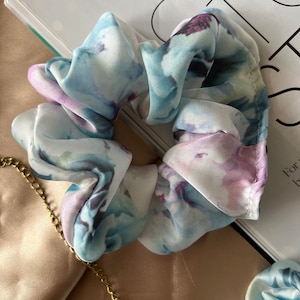 May include: A white scrunchie with a blue and purple watercolour floral print.