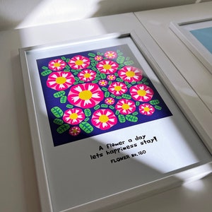 Könnte beinhalten: Ein gerahmter Kunstdruck mit einem floralen Design. Das Kunstwerk zeigt rosa Blumen mit gelben Zentren und grünen Blättern auf einem dunkelblauen Hintergrund. Der Druck enthält den Text "A flower a day lets happiness stay!" und "FLOWER No. 160".