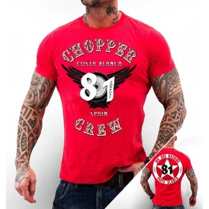 May include: Red t-shirt with a white graphic print of a motorcycle club logo. The logo features a winged design with the text "Chopper Costa Blanca 81 Spain Crew".