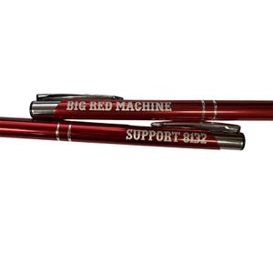 Peut inclure: Deux stylos rouges avec des détails argentés. Le stylo du haut porte l'inscription "BIG RED MACHINE" en blanc. Le stylo du bas porte l'inscription "SUPPORT 8132" en blanc. Les deux stylos ont un clip argenté.