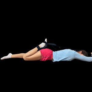 K&ouml;nnte beinhalten: Eine Person liegt auf dem Bauch, tr&auml;gt ein hellblaues Langarmshirt und rote Shorts und benutzt einen schwarzen Dehngurt. Die Person tr&auml;gt wei&szlig;e Socken und eine schwarze Kn&ouml;chelbandage.