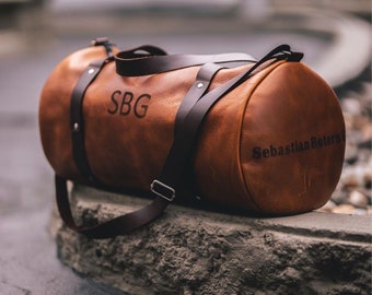 May include: A brown leather duffel bag with a black strap and the initials "SBG" embossed on the front. The bag has the name "Sebastian Botero" embossed on the side.