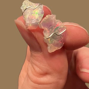 May include: Two iridescent opal stones wrapped in silver wire, a popular choice for jewellery making.