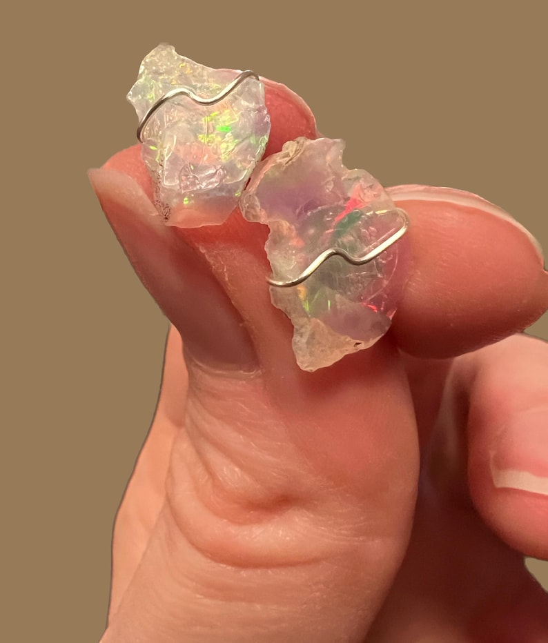 May include: Two iridescent opal stones wrapped in silver wire, a popular choice for jewellery making.