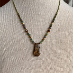 May include: A white ceramic mug with a black handle and the text "But First, Coffee" in a bold, black font. The mug is set against a blurred background, suggesting a cozy setting.