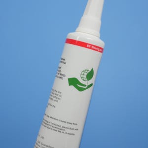 May include: A white cylindrical adhesive tube with a pointed nozzle cap. The label features a red horizontal stripe at the top with the text BY Shang pin, a green icon of a hand holding a globe with a leaf, and black printed instructional text.