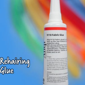 May include: A white plastic squeeze tube of 9118 Fabric Glue with a pointed nozzle and a red band near the top. The label features black text detailing usage instructions and product information. The tube is positioned vertically against a blue background.