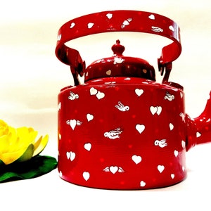 May include: Red metal teapot with a white handle and white heart and bird designs.