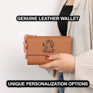 May include: A brown genuine leather wallet with a flap closure. The wallet features a black illustration of a unicorn and a butterfly. The text "GENUINE LEATHER WALLET" and "UNIQUE PERSONALIZATION OPTIONS" are displayed.