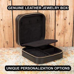 Puede incluir: Caja de joyería de cuero negro genuino con cremallera dorada, abierta para revelar un interior negro con compartimentos para joyas. Se muestra el texto "GENUINE LEATHER JEWELRY BOX" y "UNIQUE PERSONALIZATION OPTIONS".