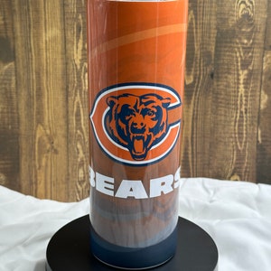 May include: A stainless steel tumbler with a Chicago Bears logo. The tumbler is orange, blue, and white with a bear head and the word "BEARS" on it.