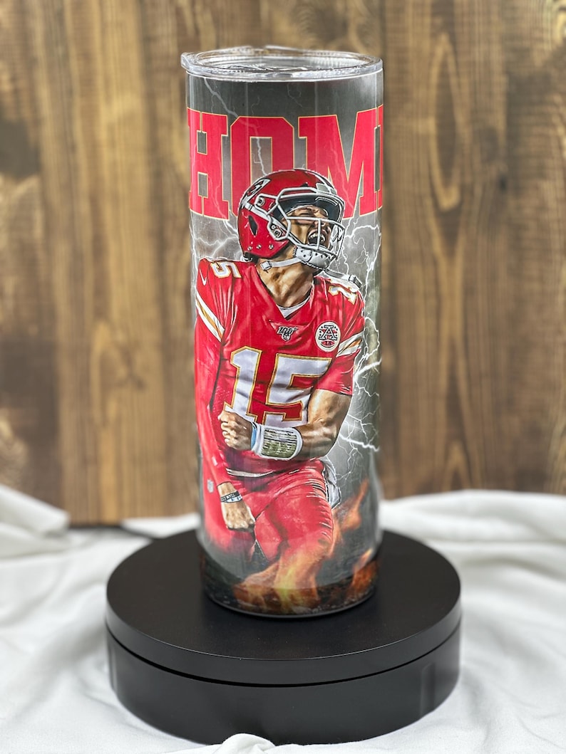 May include: A stainless steel tumbler with a black and red design featuring a football player in a red jersey with the number 15. The text "HOM" is visible on the tumbler.