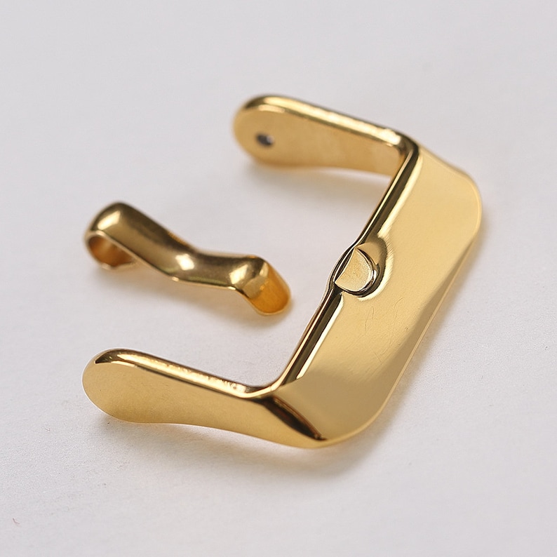 K&ouml;nnte beinhalten: Goldfarbener Metall-Uhrenarmbandverschluss mit einem Federschloss. Die Schlie&szlig;e ist f&uuml;r ein Uhrenarmband mit einer Breite von 20 mm ausgelegt.