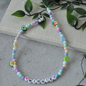 May include: A colorful beaded necklace with fruit charms and the name "WINNIE" spelled out in white beads with pink hearts.