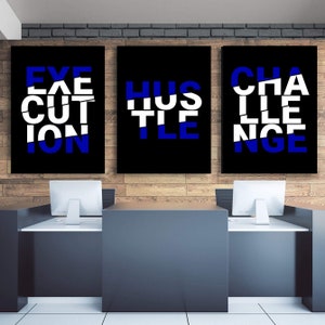 May include: Three black framed wall art pieces with white and blue text. The first reads "EXECUTION", the second "HUSTLE", and the third "CHALLENGE". The art is displayed above a desk with two computer monitors.