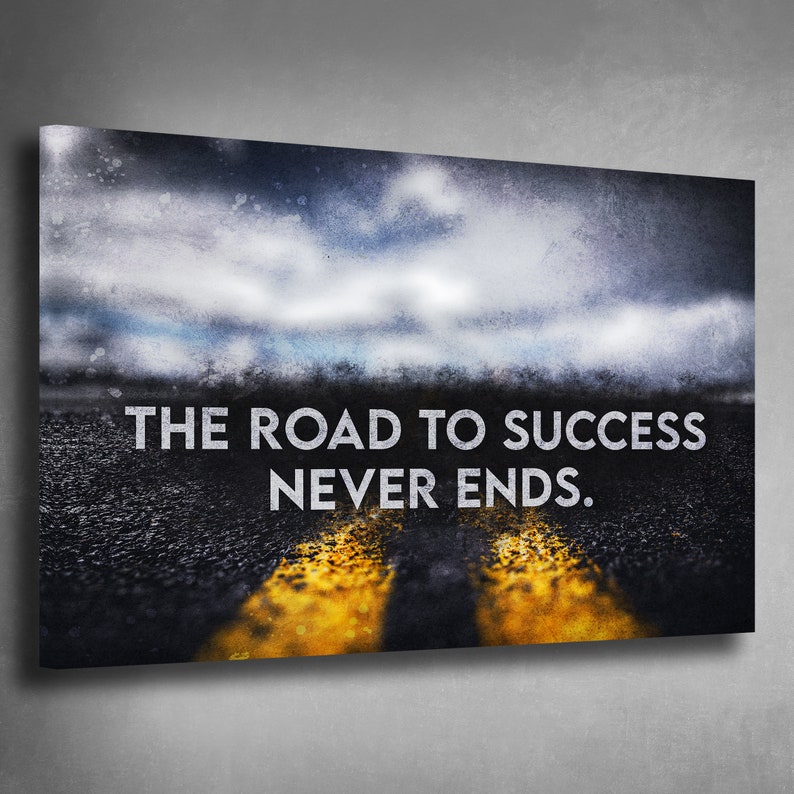 K&ouml;nnte beinhalten: Leinwanddruck mit einer Stra&szlig;e mit gelben Linien unter einem bew&ouml;lkten Himmel. Der wei&szlig;e Text lautet "THE ROAD TO SUCCESS NEVER ENDS". Das Kunstwerk hat einen strukturierten, verwitterten Look.
