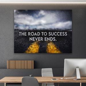 K&ouml;nnte beinhalten: Leinwanddruck mit dem Text "THE ROAD TO SUCCESS NEVER ENDS." Das Bild zeigt eine Stra&szlig;e mit gelben Linien, die zu einem bew&ouml;lkten Himmel f&uuml;hrt. Das Kunstwerk wird an einer Wand &uuml;ber einem Holzschreibtisch pr&auml;sentiert.
