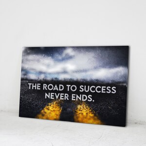K&ouml;nnte beinhalten: Leinwanddruck mit einer Stra&szlig;e, die zu einem bew&ouml;lkten Himmel f&uuml;hrt. Der wei&szlig;e Text lautet "THE ROAD TO SUCCESS NEVER ENDS". Die Stra&szlig;e hat gelbe Fahrbahnmarkierungen.
