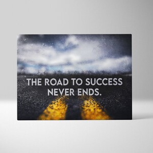 K&ouml;nnte beinhalten: Leinwanddruck mit einer Stra&szlig;e mit gelben Linien unter einem bew&ouml;lkten Himmel. Der wei&szlig;e Text lautet "THE ROAD TO SUCCESS NEVER ENDS". Das Bild hat ein motivierendes Thema, geeignet f&uuml;r die Dekoration und um zu inspirieren.
