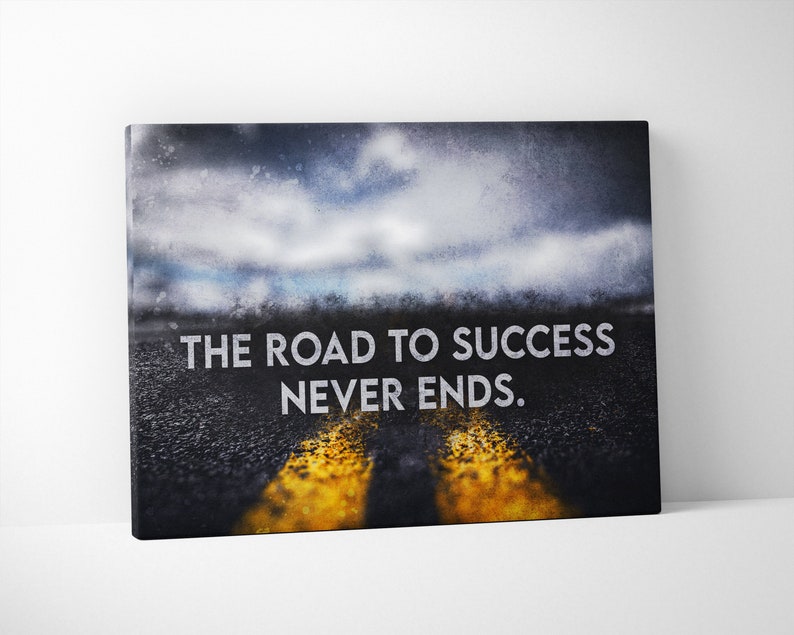 K&ouml;nnte beinhalten: Leinwanddruck mit einer Stra&szlig;e mit gelben Linien unter einem bew&ouml;lkten Himmel. Der wei&szlig;e Text lautet "THE ROAD TO SUCCESS NEVER ENDS". Geeignet f&uuml;r die Inneneinrichtung.