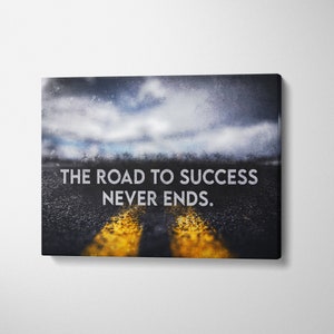K&ouml;nnte beinhalten: Leinwanddruck mit einer Stra&szlig;e mit gelben Linien, die zu einem verschwommenen Horizont unter einem bew&ouml;lkten Himmel f&uuml;hrt. Der Text "THE ROAD TO SUCCESS NEVER ENDS" ist in Wei&szlig; dargestellt.
