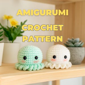 Puede incluir: Dos amigurumis de pulpo de ganchillo, uno verde menta y otro blanco, están sobre una estantería de madera. Cada uno tiene ojos negros y mejillas rosas. El texto "AMIGURUMI CROCHET PATTERN" se muestra arriba.