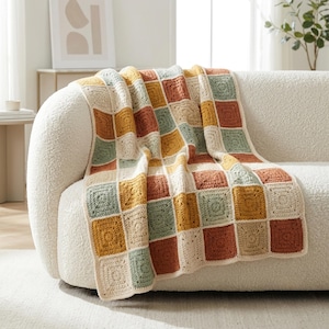 May include: A crochet blanket featuring a grid of square motifs in alternating colors of cream, mustard yellow, sage green, and terracotta orange. The textile is constructed from individual yarn squares joined together in a repeating pattern.