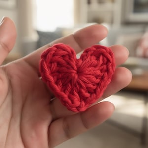 Peut inclure: Gros plan sur un cœur rouge crocheté à la main. La forme de cœur est clairement définie avec une surface texturée créée par les points de crochet. La couleur rouge vif est vibrante, suggérant un thème d'amour ou d'affection.