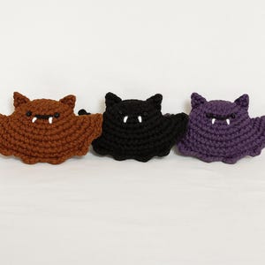 Puede incluir: Tres murci&eacute;lagos de ganchillo en marr&oacute;n, negro y morado. Cada murci&eacute;lago tiene colmillos blancos y peque&ntilde;os ojos negros. Los murci&eacute;lagos hechos a mano tienen un aspecto texturizado, perfectos para decoraciones de Halloween o regalos tem&aacute;ticos.