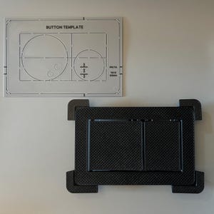 Puede incluir: Una plantilla de botón blanca con el texto "BUTTON TEMPLATE" y un objeto rectangular negro texturizado. La plantilla tiene recortes circulares y rectangulares. El objeto rectangular tiene un patrón similar a una cuadrícula.