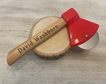 Op de afbeelding: Een rode en houten pizzames in de vorm van een bijl met een houten handvat waarop "David Washburn" staat.