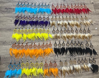 May include: A collection of dreamcatcher keychains in various colors, including blue, red, purple, yellow, orange, black, and tan. Each keychain features a small dreamcatcher design with feathers and a metal ring. The word "Mystic" is visible in the upper left corner.