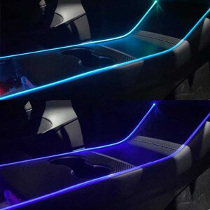 May include: Two images showing a car interior with a blue and a turquoise LED light strip installed along the center console. The light strip is visible in the center console and along the edge of the passenger seat.