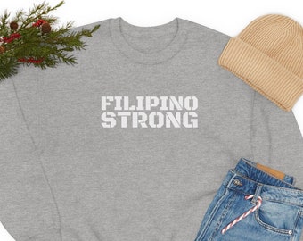 Può includere: Una felpa grigia con la scritta "FILIPINO STRONG" in lettere bianche. La felpa è abbinata a jeans blu, un berretto beige e scarpe da ginnastica nere.