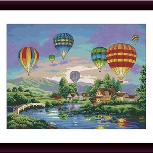 Op de afbeelding: Een kleurrijk tafereel met luchtballonnen die over een klein stadje en een meer zweven. De ballonnen zijn in verschillende tinten rood, geel, blauw en groen. Het stadje heeft huizen met witte versieringen en groene bomen. Het meer is diepblauw met reflecties van de ballonnen.