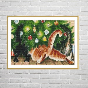 May include: A framed cross-stitch embroidery depicting three cats in front of a decorated Christmas tree. One cat is black, one is orange tabby, and one is dark gray. The tree features green needles and various colorful round ornaments.