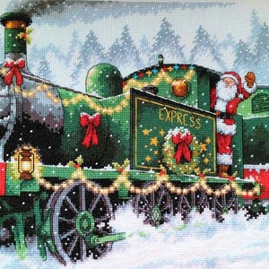 Puede incluir: Un bordado de punto de cruz de un tren navideño verde con Papá Noel saludando. El tren está adornado con lazos rojos, luces y la palabra "EXPRESS" en un letrero. La nieve cae alrededor del tren y en el fondo.