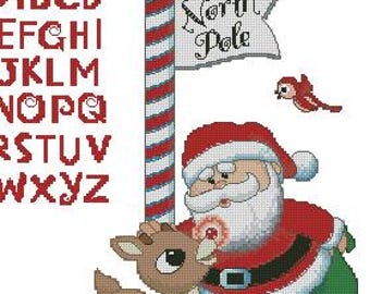 May include: A cross-stitch design featuring Santa Claus, a reindeer, and the text "North Pole." Santa wears a red suit and hat, holding a green sack. The reindeer is brown. The name "Eduardo" is at the top, with an alphabet chart on the left.