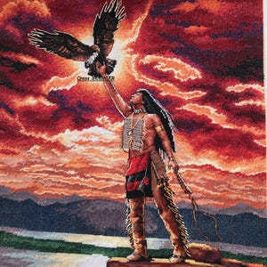 May include: A cross-stitch depicting a Native American figure holding an eagle against a fiery sunset. The figure is adorned in traditional attire, standing on a rock formation. The text "Cross Stitch TR" is visible.