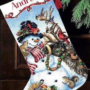 May include: A Christmas stocking with a snowman design, wearing a red and white striped scarf, and surrounded by squirrels and birds. The name "Andrew" is printed in red at the top, with a red ribbon and decorative accents.