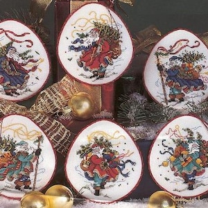 Può includere: Sei ornamenti natalizi ovali con disegni a punto croce di Babbo Natale che trasporta un albero di Natale. Ogni ornamento ha un bordo rosso e uno sfondo bianco. Babbo Natale indossa abiti rossi, blu e verdi.