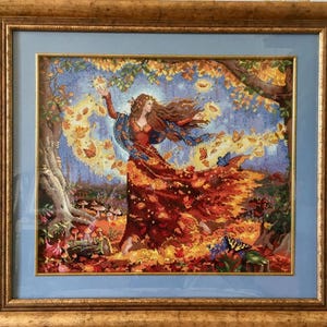 Könnte beinhalten: Gerahmtes Kreuzstich-Kunstwerk, das eine Frau in einem fließenden roten und orangefarbenen Kleid zeigt, umgeben von fallenden Blättern und Schmetterlingen. Das Kunstwerk ist in einer Waldszene mit blauem Himmel und einem goldenen Rahmen angesiedelt.