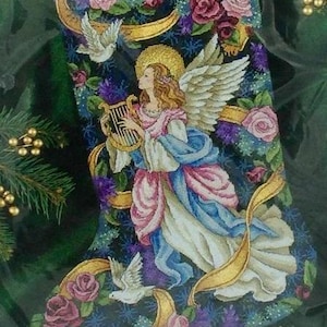 May include: Embroidered Christmas stocking featuring an angel playing a harp, surrounded by roses, doves, and the name "Samantha" on a banner. The stocking has a dark blue background with gold accents.