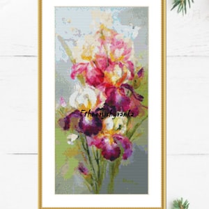 May include: A framed cross-stitch embroidery featuring a bouquet of colorful irises in shades of purple, pink, white, and yellow. The flowers are arranged in a vase and the background is a light blue and green watercolor wash. The text "Ethnoryushyanka" is visible in the lower center of the image.