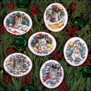Peut inclure: Six ornements ovales brodés représentant des chatons dans des scènes de Noël. Chaque ornement présente un chaton différent entouré de verdure de Noël, de baies et d'éléments décoratifs. Les ornements sont posés sur un fond de branches de sapin et de boules de Noël.