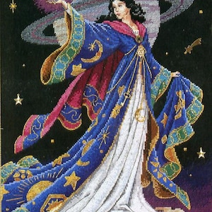 May include: Cross-stitch artwork of a woman in a flowing blue and white gown, holding a crystal ball. The gown is adorned with gold stars and crescent moons. The background features a planet, stars, and a crescent moon.